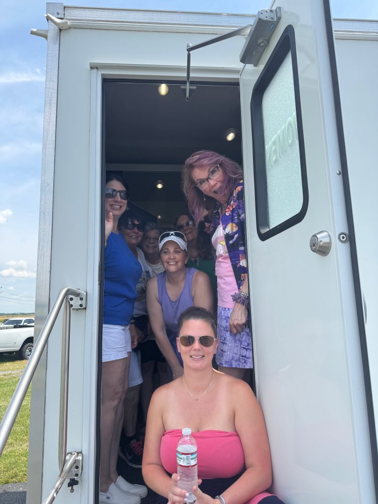 cathi and her friends pose in a portable bathroom because she wants you to know when your real estate transaction is in the toilet you should call cathi miller